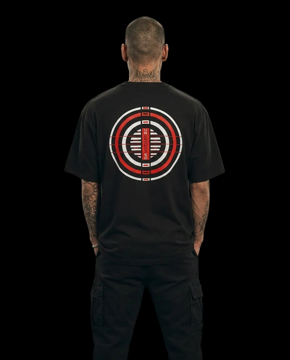 Person wearing a black unprompted t-shirt with a red and white circular logo on the back against a dark background